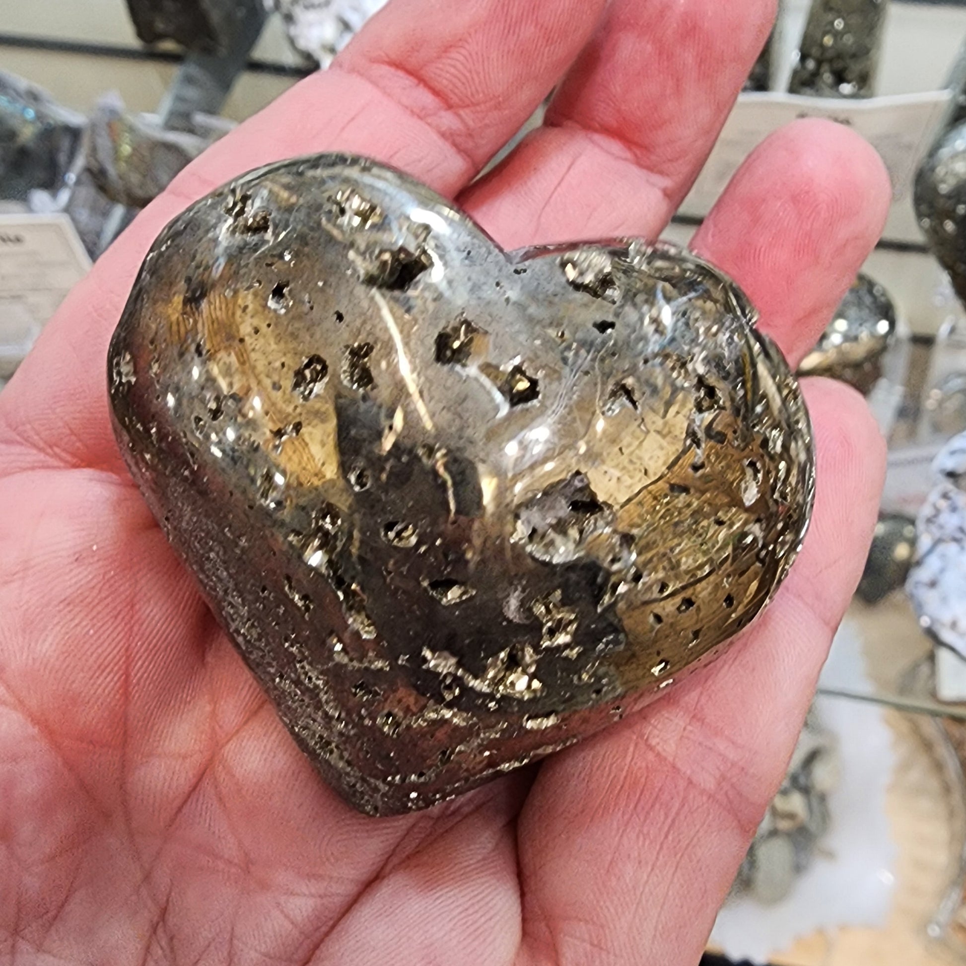Heart-shaped metallic object held in a hand with blurred background